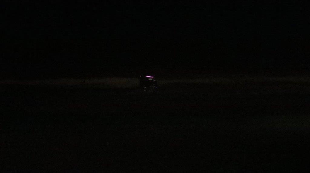 A car at night with a bright light with Marfa lights in the background

Description automatically generated