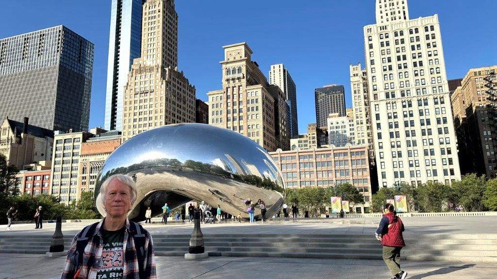 A person standing in front of a large silver sculpture in Millennium Park

Description automatically generated