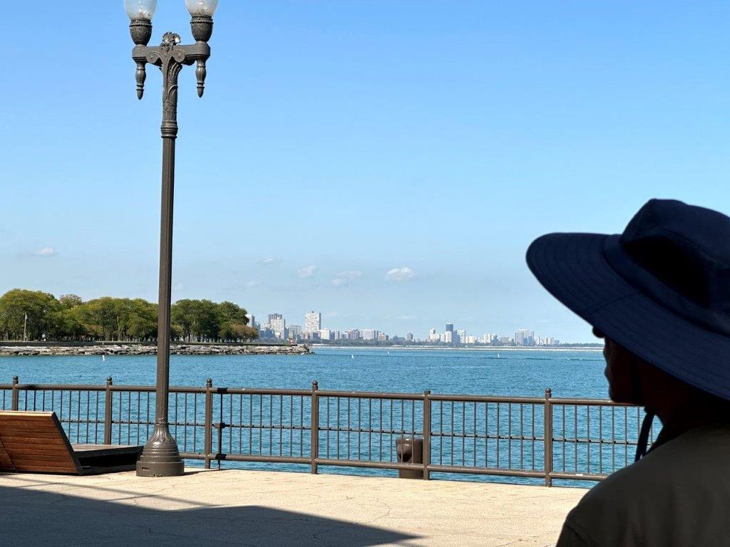 A person wearing a hat looking at a body of water

Description automatically generated