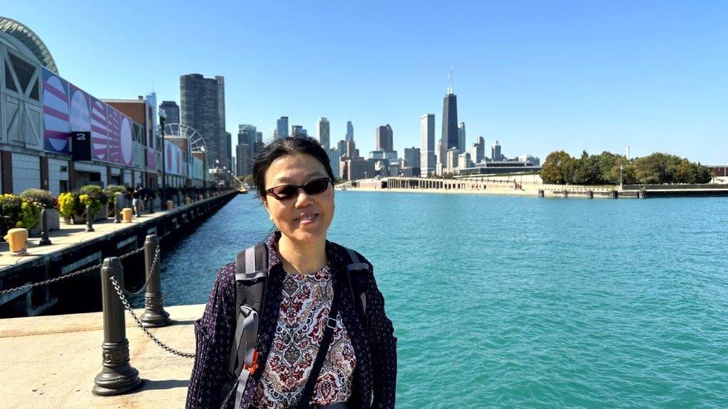 A person standing on a dock with a city in the background

Description automatically generated