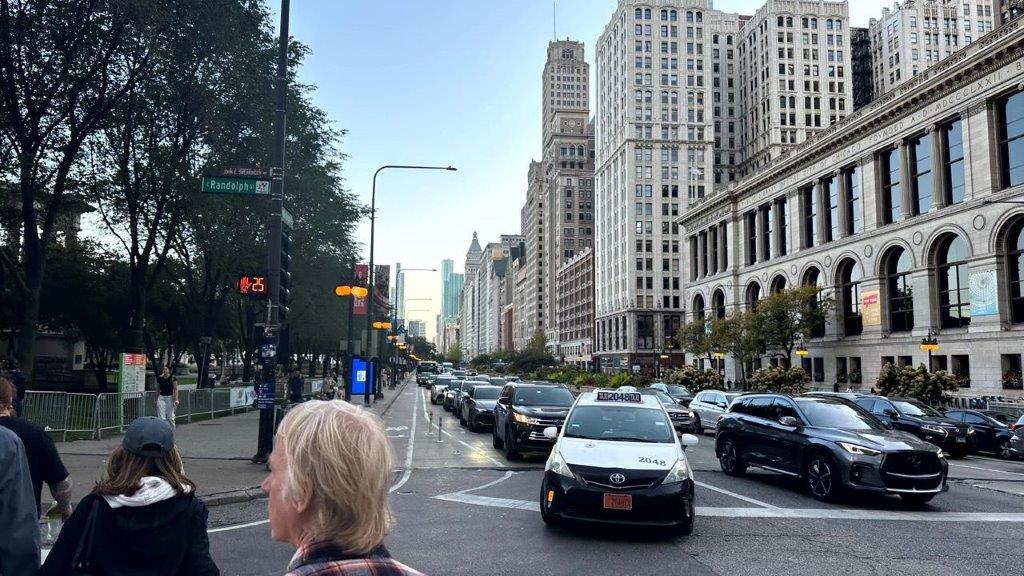 A person standing on a street with cars and buildings in the background

Description automatically generated