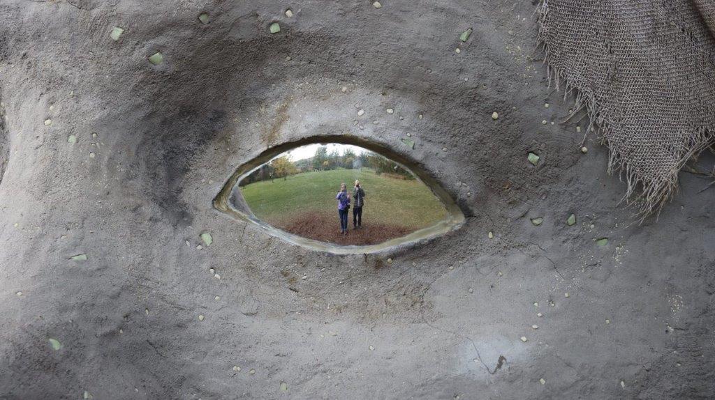 A couple of people standing in a hole in a rock

Description automatically generated