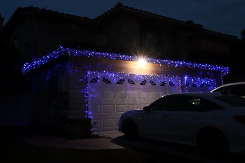 A car parked in front of a house with blue lights

Description automatically generated