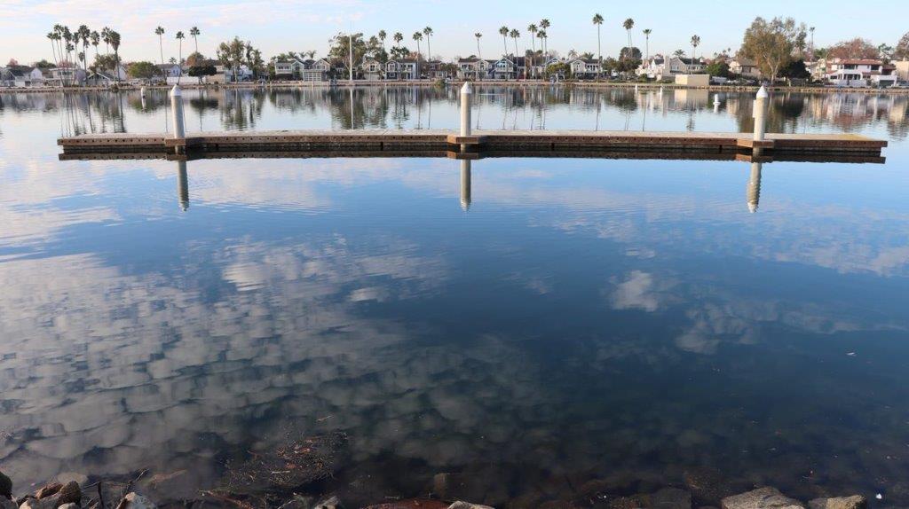 A body of water with a dock and buildings in the background

Description automatically generated