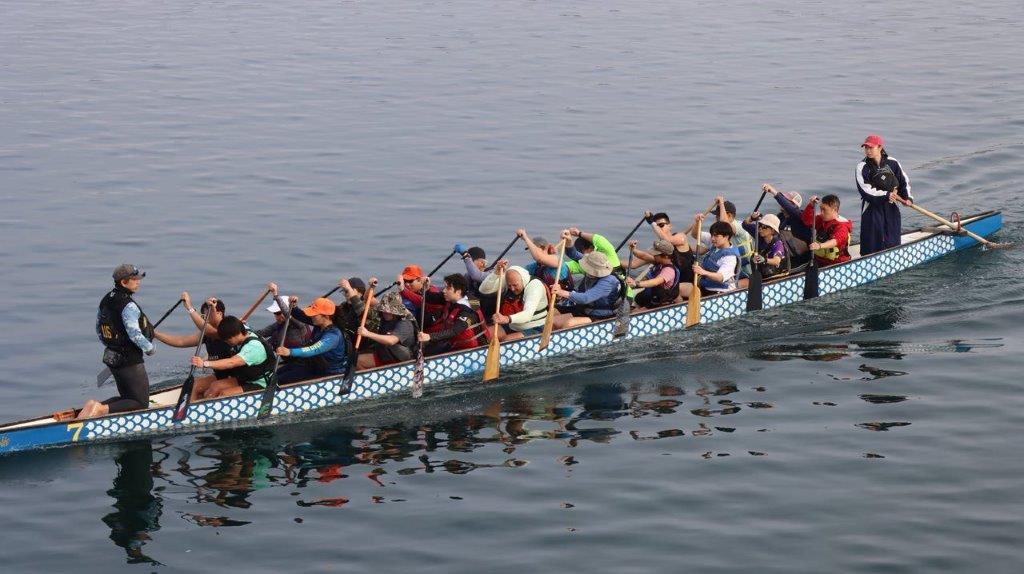 A group of people rowing a boat

Description automatically generated