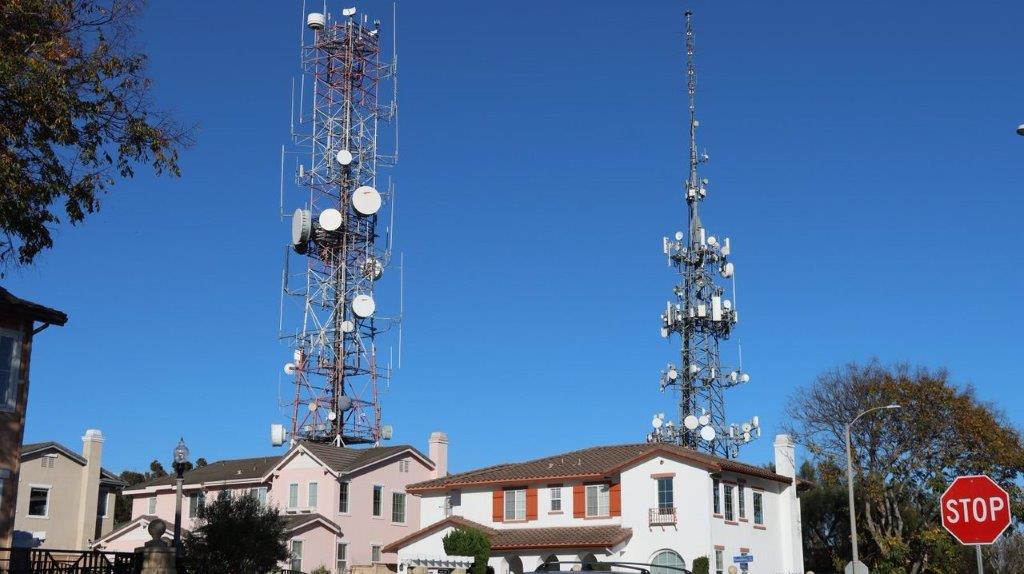 A large tower with antennas on top of a house with Watts Towers in the background

Description automatically generated
