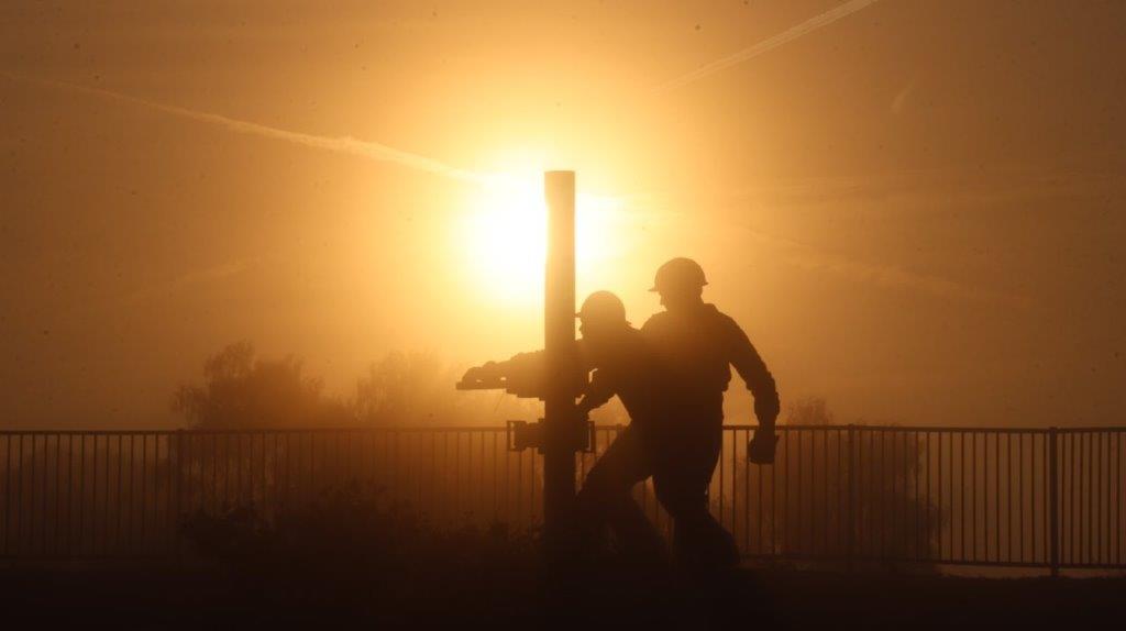 A silhouette of men working on a pole

AI-generated content may be incorrect.