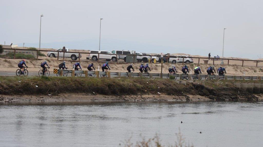A group of people riding bikes near a body of water

Description automatically generated