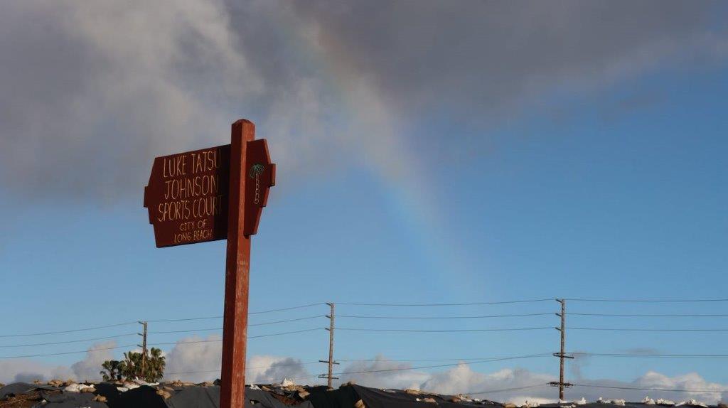 A rainbow in the sky above a sign

Description automatically generated