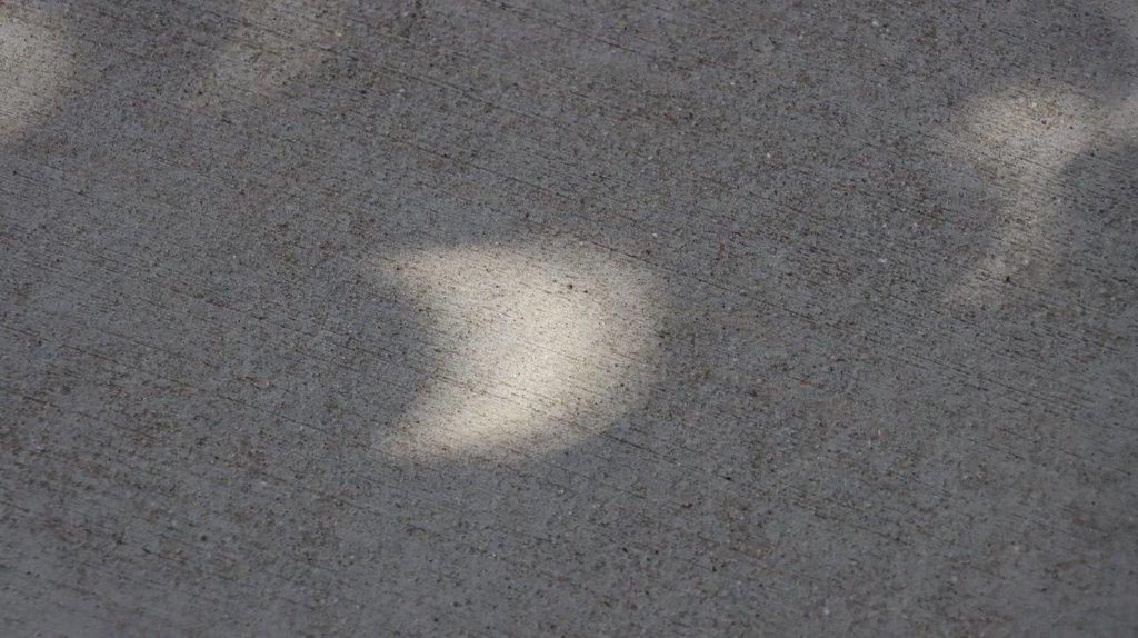 A shadow of a moon on the ground

Description automatically generated