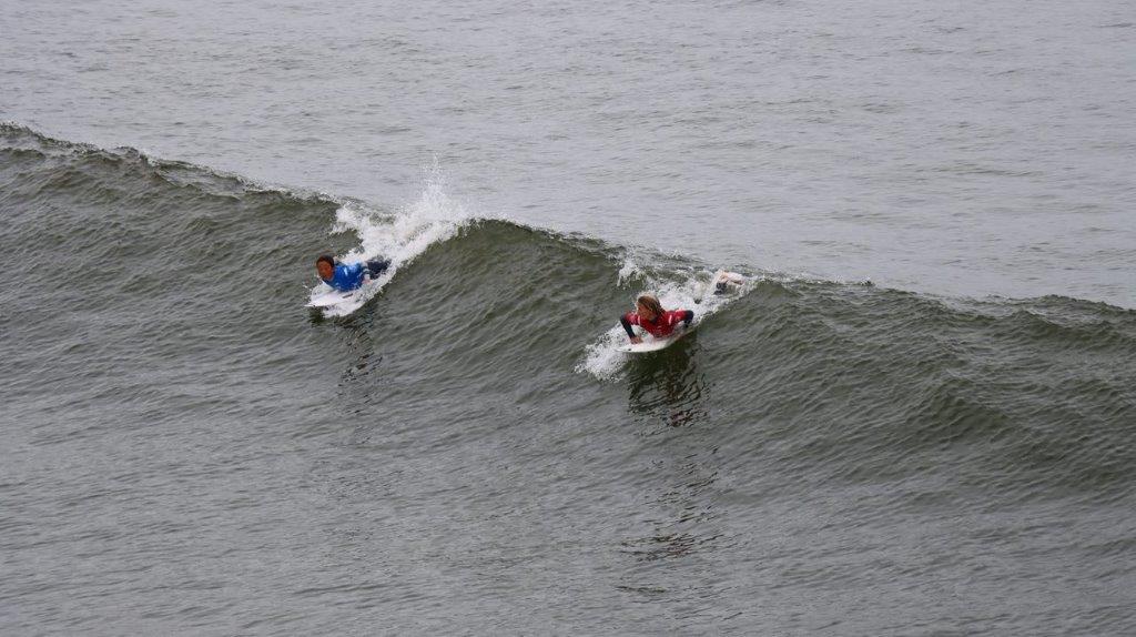 A couple of surfers riding a wave

Description automatically generated