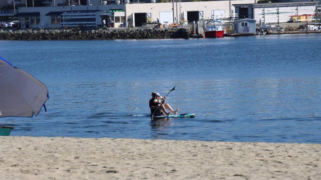 A person on a paddle board on a beach

Description automatically generated