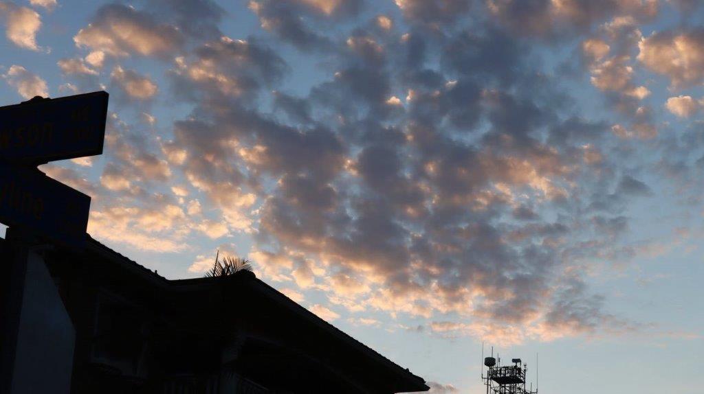 A silhouette of a building and a cloudy sky

Description automatically generated