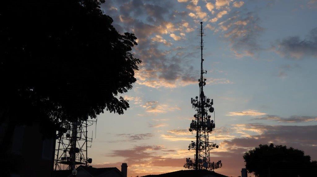 A silhouette of a tower with a tree and clouds in the sky

Description automatically generated