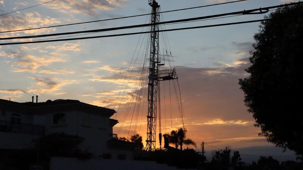 A tower with power lines and a building in the background

Description automatically generated