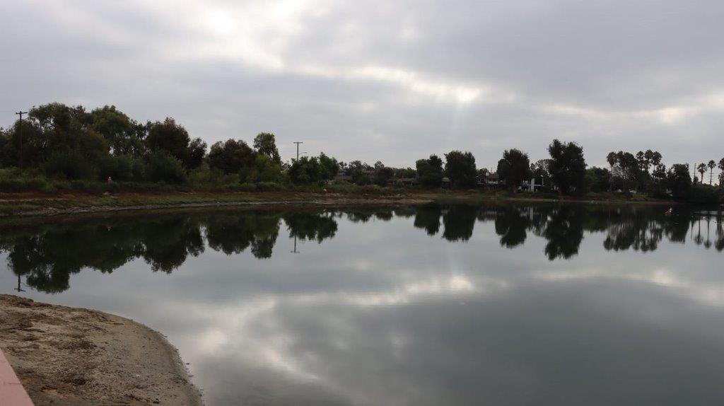 A body of water with trees and clouds in the sky

Description automatically generated