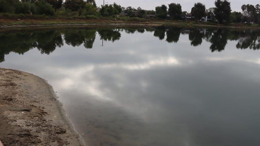 A body of water with trees and clouds reflected in the water

Description automatically generated