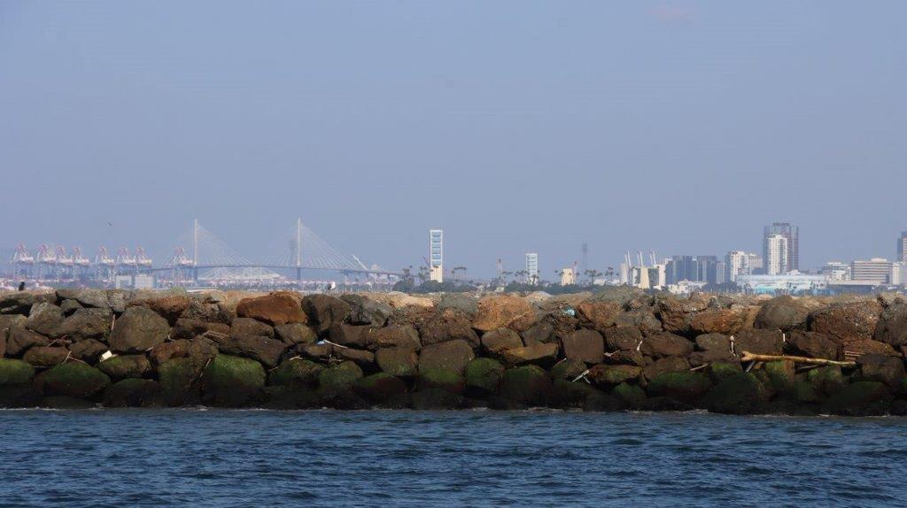 A rock wall with a city in the background

Description automatically generated