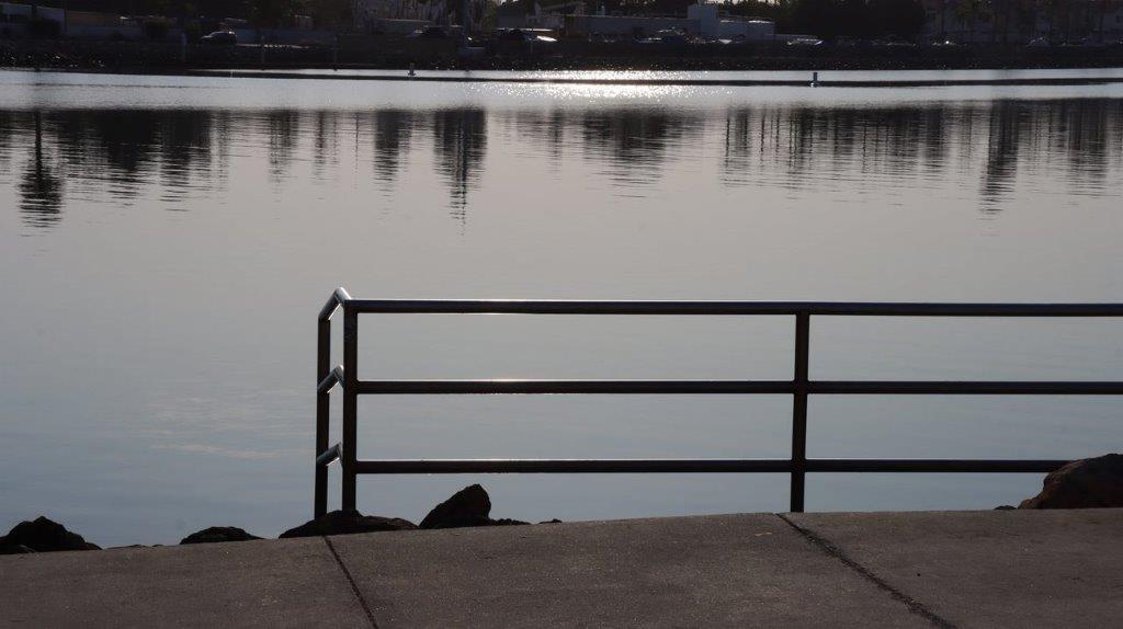 A railing on a dock next to a body of water

Description automatically generated